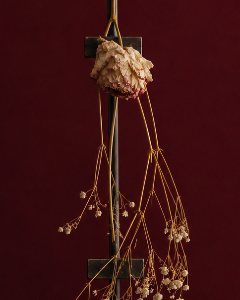 Up close decorative plant sculpture. A peony standing because of the metal easel supporting in, standing on a wooden pedestal against a dark red background