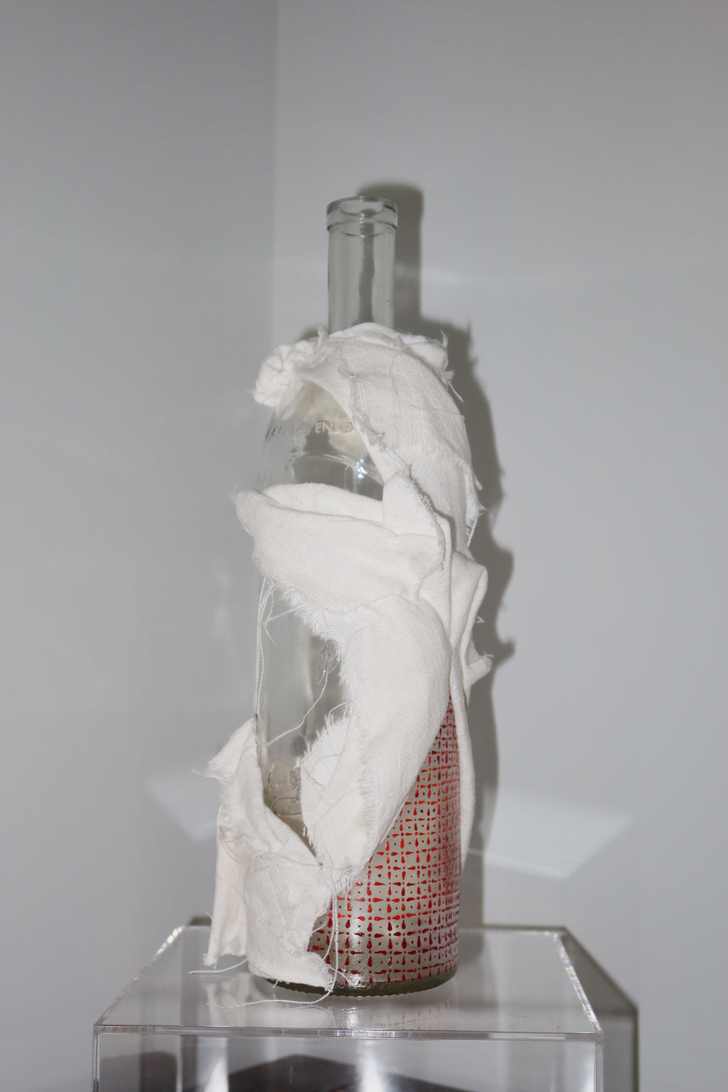 Glass bottle with white linen, hand-painted red pattern painted on glass against a white background
